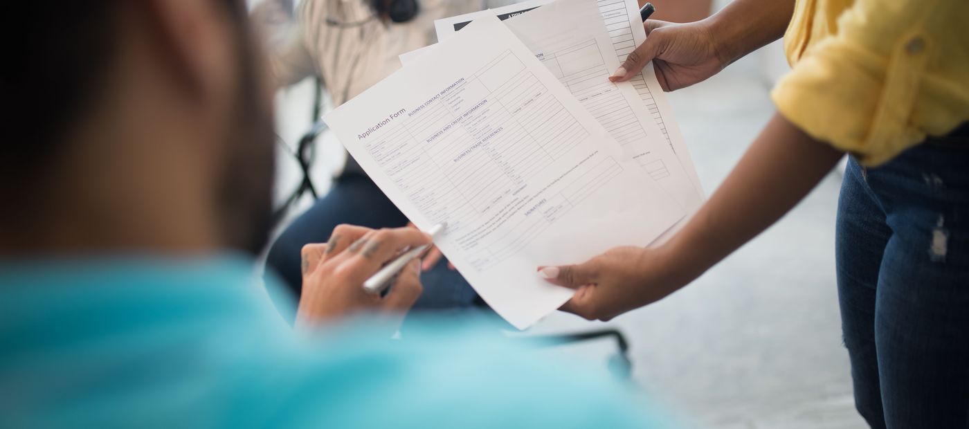 A completed application form being handed across a desk