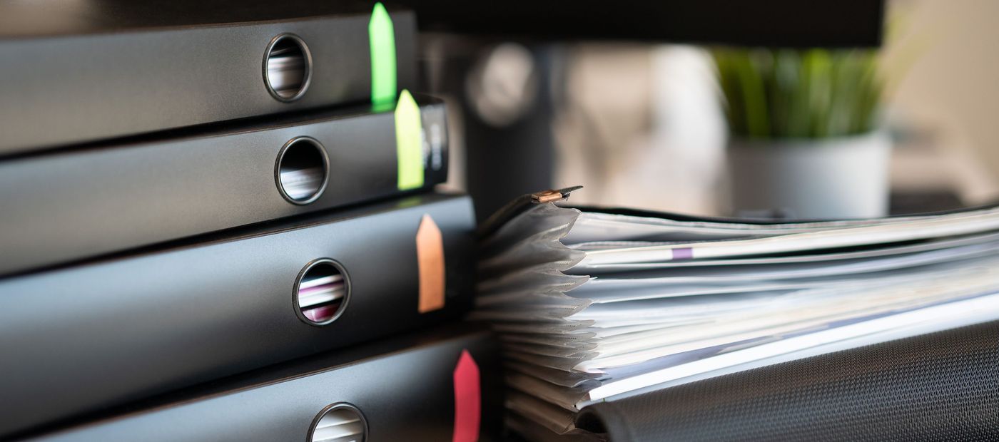 Labelled binders and document files stacked on an office desk
